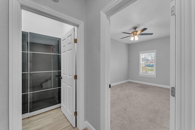 interior space featuring a textured ceiling, a textured wall, carpet flooring, and baseboards