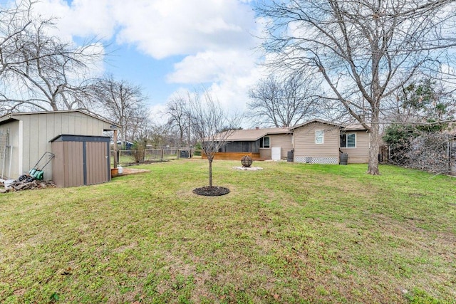 view of yard with a storage shed, fence, a fire pit, and an outbuilding