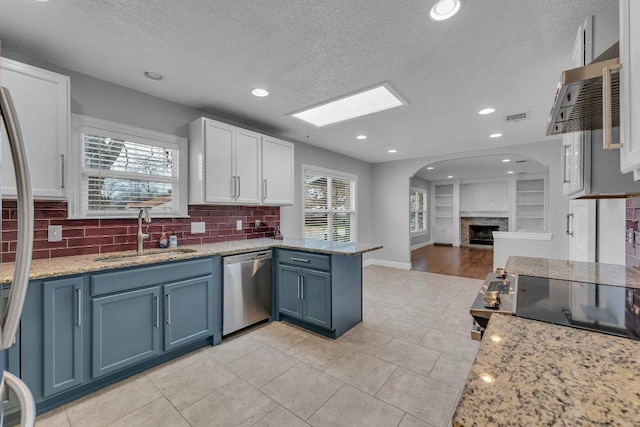 kitchen featuring a peninsula, a sink, visible vents, open floor plan, and dishwasher