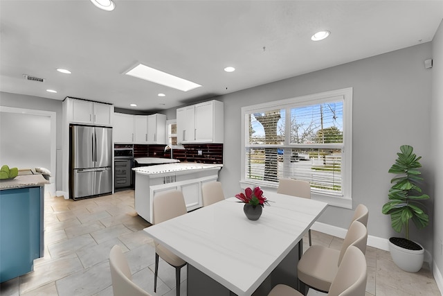 kitchen with baseboards, backsplash, freestanding refrigerator, light countertops, and a sink