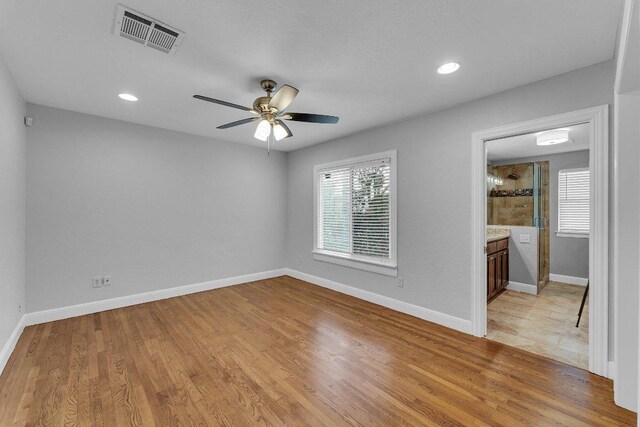 spare room with light wood finished floors, visible vents, and a healthy amount of sunlight