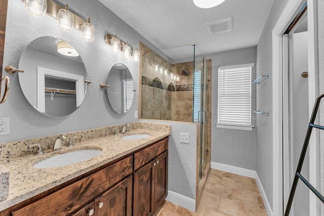 bathroom featuring double vanity, a sink, visible vents, and a shower stall