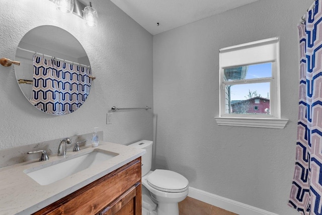 bathroom with baseboards, a textured wall, toilet, tile patterned flooring, and vanity