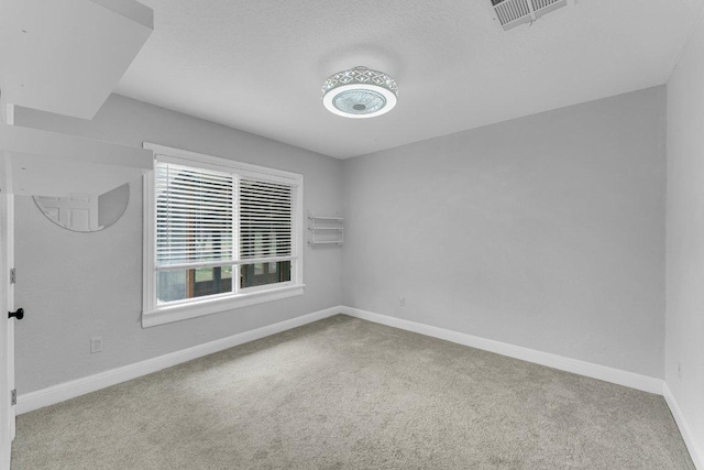 unfurnished room with baseboards, a textured ceiling, visible vents, and carpet flooring