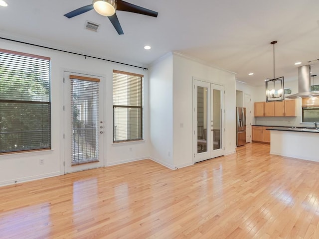 interior space featuring island exhaust hood, stainless steel refrigerator with ice dispenser, light wood finished floors, dark countertops, and light brown cabinets