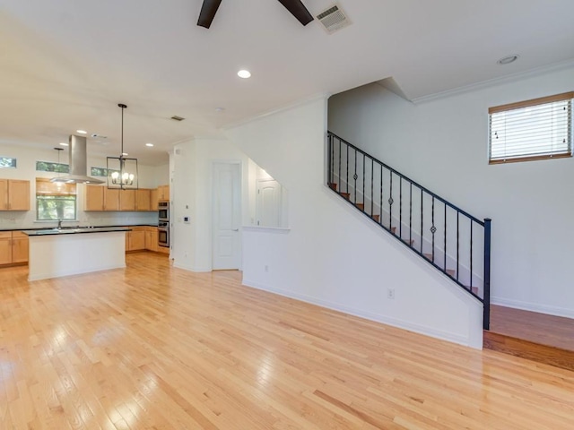 unfurnished living room with stairs, light wood finished floors, visible vents, and baseboards