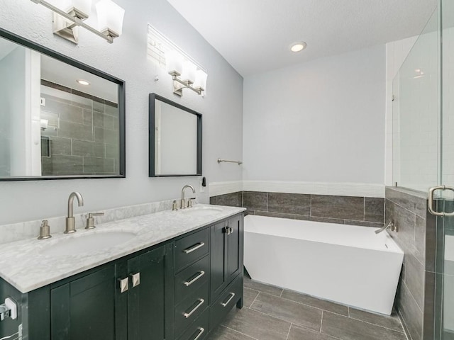 bathroom featuring double vanity, a freestanding tub, a stall shower, and a sink