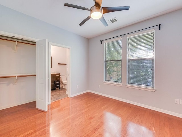 unfurnished bedroom with light wood finished floors, baseboards, visible vents, ensuite bathroom, and a closet