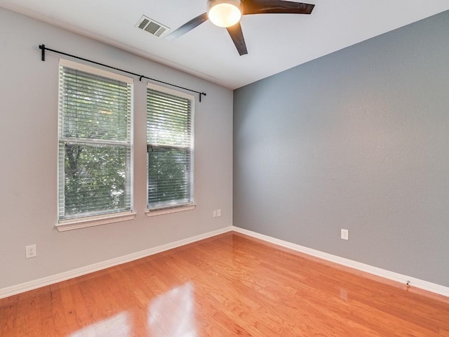 empty room featuring ceiling fan, wood finished floors, visible vents, and baseboards