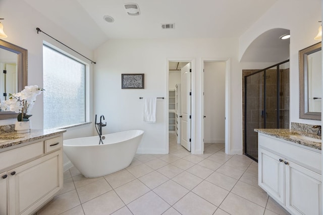 bathroom with tile patterned flooring, visible vents, vaulted ceiling, a freestanding bath, and a stall shower