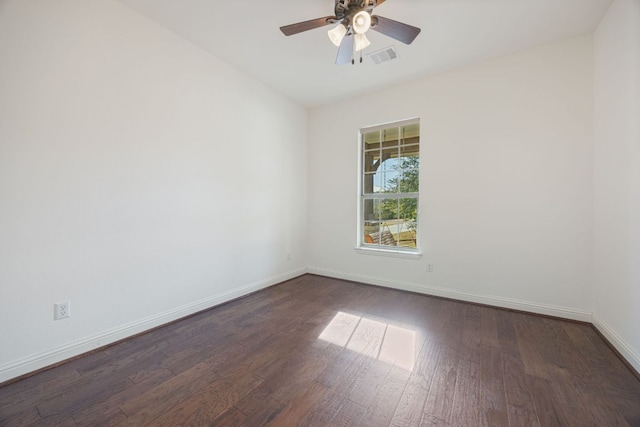 spare room featuring visible vents, dark wood finished floors, baseboards, and ceiling fan