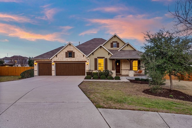 view of front of home with a garage, stone siding, fence, and driveway