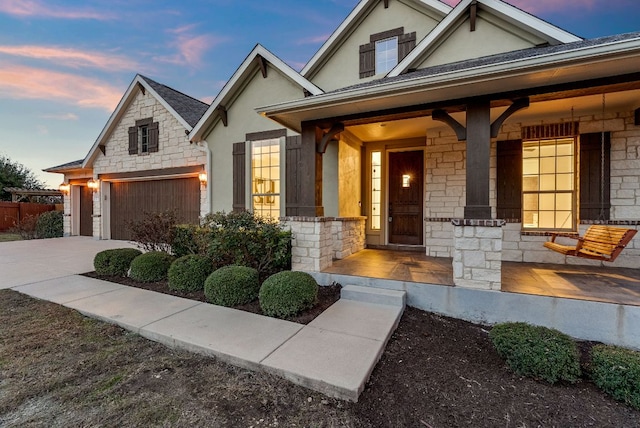 view of front of house with stone siding, a porch, and stucco siding