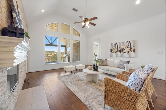 living room with arched walkways, high vaulted ceiling, a fireplace, visible vents, and hardwood / wood-style floors