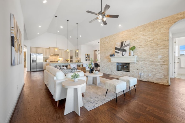 living area with a ceiling fan, high vaulted ceiling, wood finished floors, and a glass covered fireplace