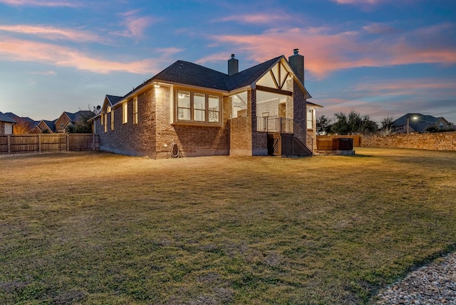 exterior space with a yard, a chimney, fence, and brick siding