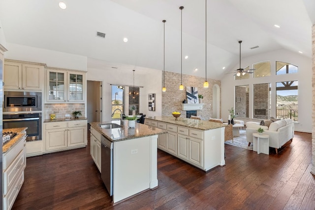 kitchen with a center island with sink, visible vents, appliances with stainless steel finishes, a fireplace, and a sink