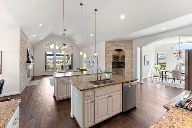 kitchen featuring dark wood finished floors, an island with sink, stainless steel appliances, a fireplace, and a sink