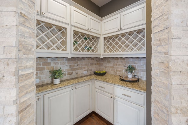 kitchen featuring tasteful backsplash, light stone counters, and white cabinets