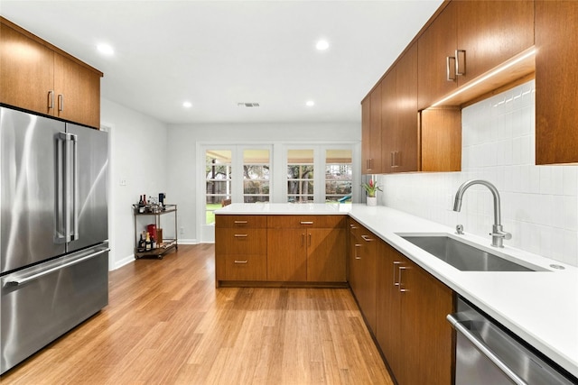 kitchen featuring stainless steel appliances, a sink, visible vents, light wood-style floors, and light countertops