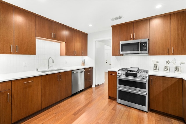 kitchen featuring light countertops, visible vents, appliances with stainless steel finishes, a sink, and light wood-type flooring