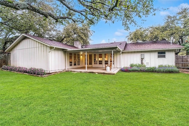 back of property featuring board and batten siding, a patio area, a yard, and fence