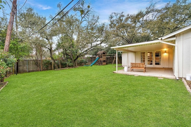 view of yard with a patio area, a playground, a fenced backyard, and french doors