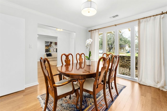 dining room with light wood-style flooring, visible vents, ornamental molding, and baseboards