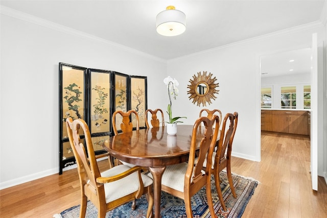 dining space with baseboards, light wood-style flooring, and crown molding