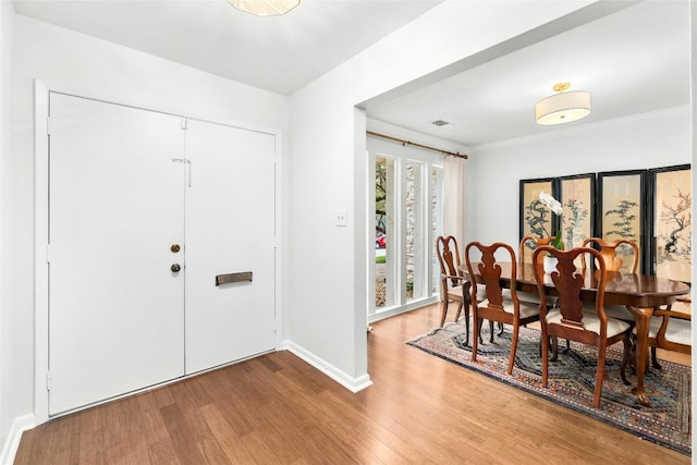 dining room featuring ornamental molding, baseboards, and wood finished floors