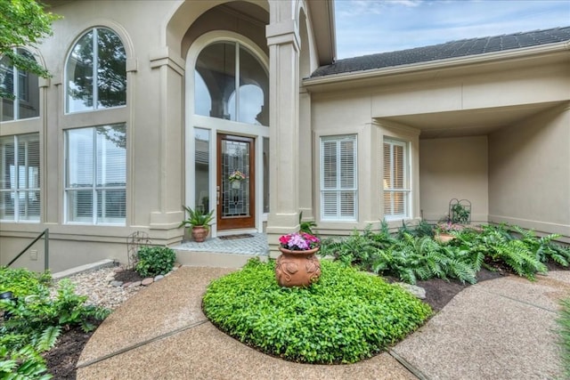 property entrance with a shingled roof and stucco siding