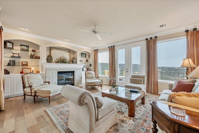 living room with light wood finished floors, a wealth of natural light, a fireplace, and visible vents