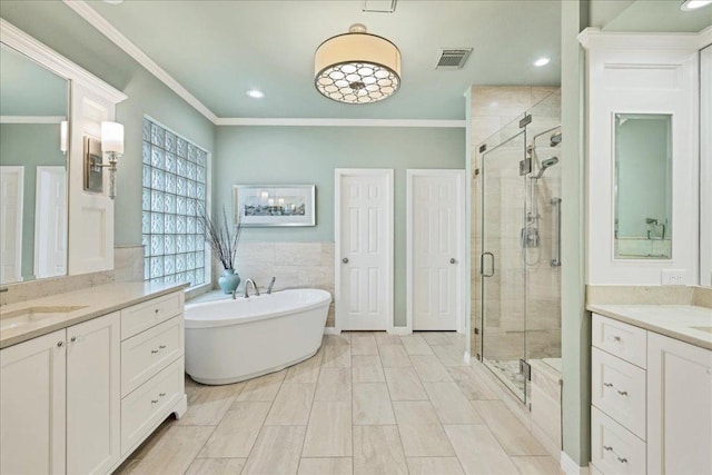 bathroom featuring a sink, visible vents, a freestanding bath, ornamental molding, and a stall shower