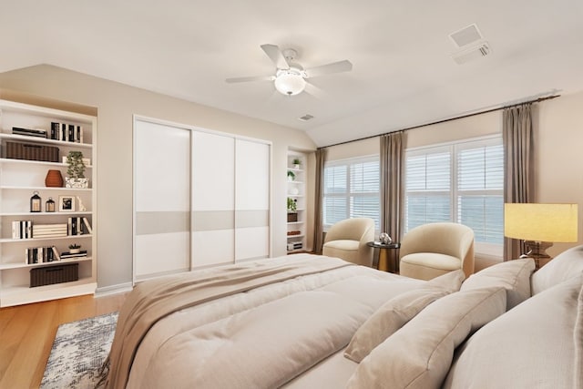 bedroom with lofted ceiling, ceiling fan, wood finished floors, visible vents, and a closet