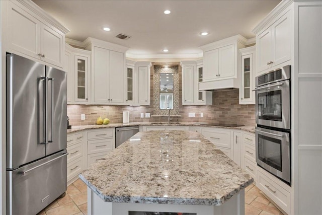 kitchen with appliances with stainless steel finishes, visible vents, a sink, and tasteful backsplash