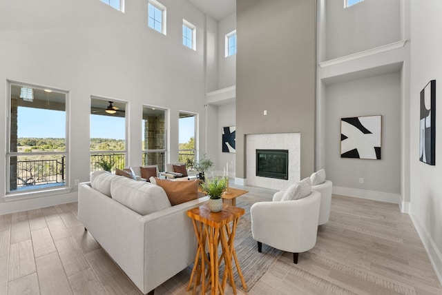 living room featuring light wood-style flooring, baseboards, and a glass covered fireplace