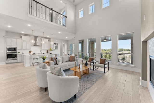 living room featuring a glass covered fireplace, light wood-style flooring, baseboards, and recessed lighting