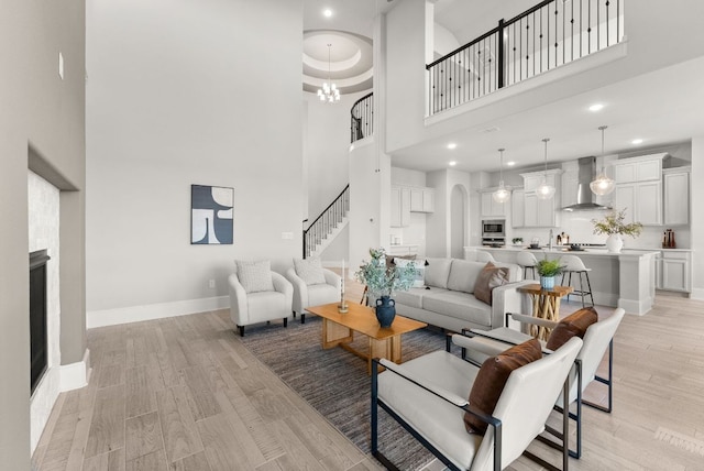 living room featuring light wood-type flooring, a fireplace, stairway, and baseboards