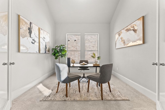 carpeted dining room with lofted ceiling and baseboards