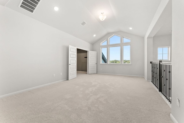 unfurnished bedroom with vaulted ceiling, light colored carpet, visible vents, and baseboards