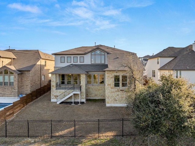 back of property featuring stone siding and a fenced backyard