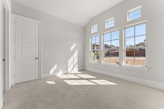 carpeted empty room featuring lofted ceiling and baseboards