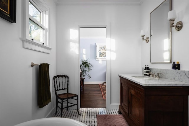 bathroom featuring baseboards, crown molding, and vanity