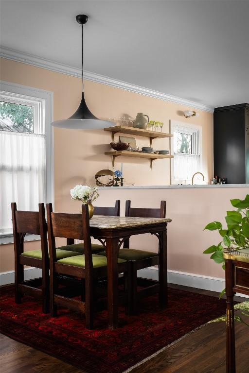 dining space featuring crown molding, baseboards, and wood finished floors