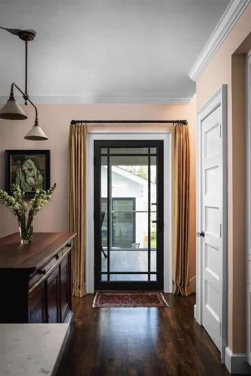 doorway featuring ornamental molding and dark wood finished floors