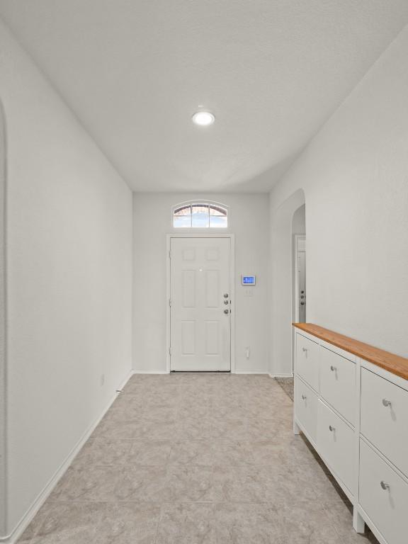 foyer entrance with arched walkways and baseboards