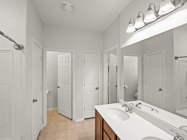 full bathroom featuring a closet, a sink, toilet, and double vanity