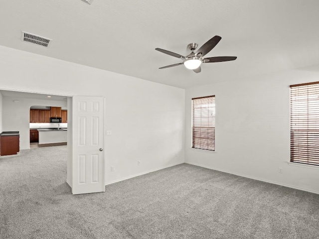 unfurnished room with light carpet, a ceiling fan, visible vents, and a wealth of natural light