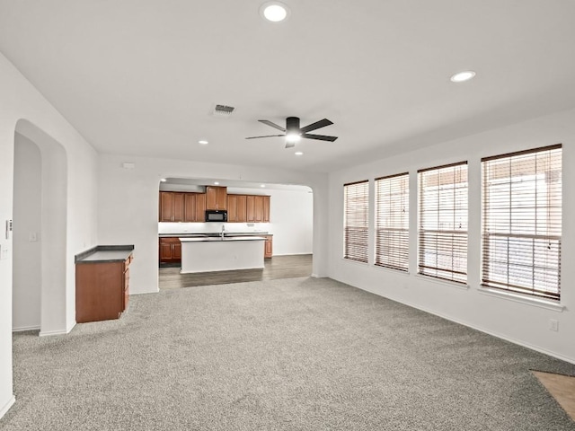 unfurnished living room featuring visible vents, arched walkways, ceiling fan, carpet flooring, and recessed lighting