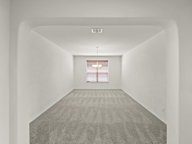 empty room with light carpet, baseboards, visible vents, arched walkways, and an inviting chandelier